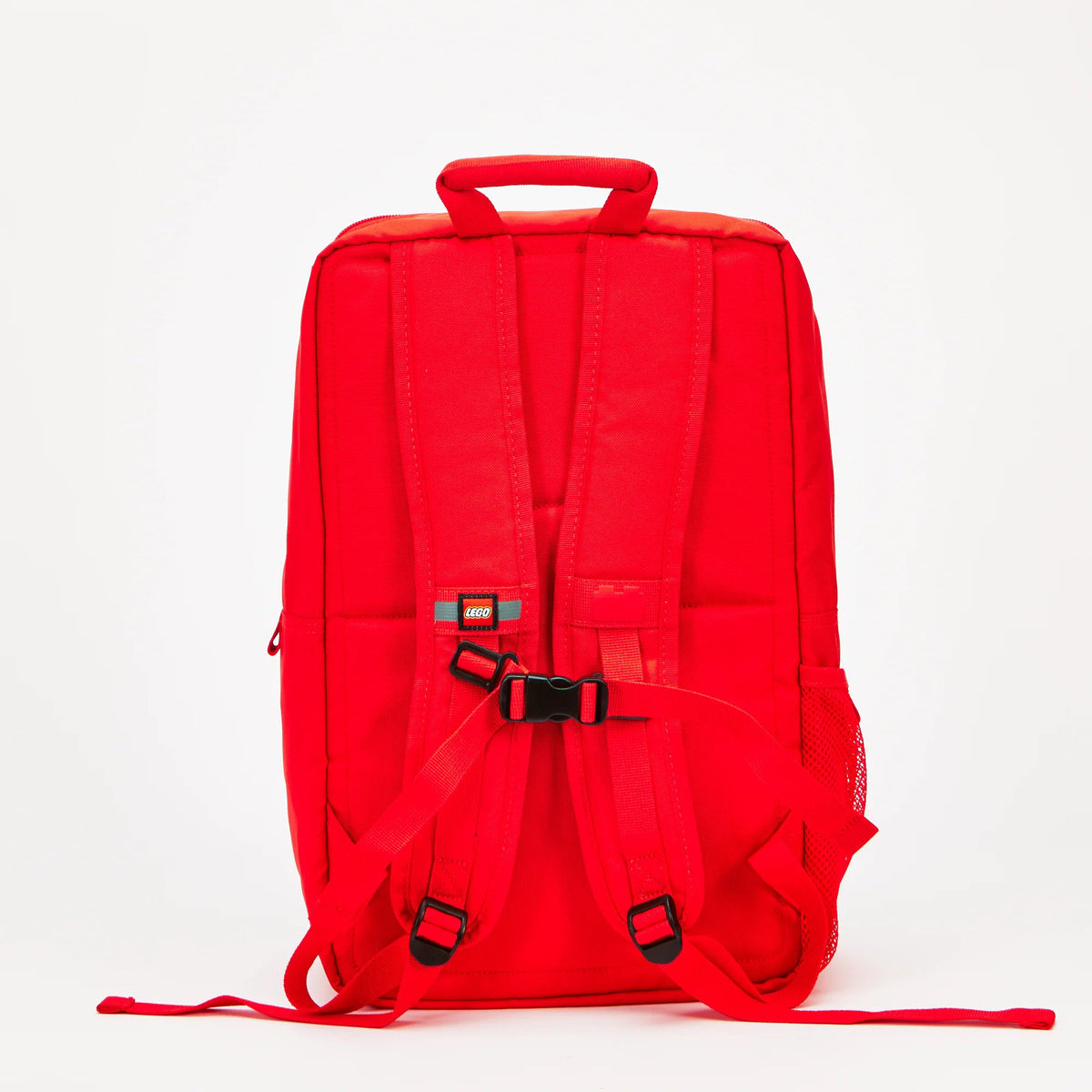 Back view of a bright red LEGO® Brick Backpack - ONLINE ONLY, featuring adjustable shoulder straps and a chest buckle.