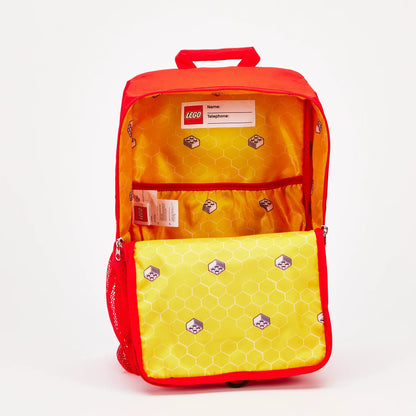 Open red LEGO® Brick Backpack - ONLINE ONLY with a yellow interior, brick-patterned lining, and a name tag label.