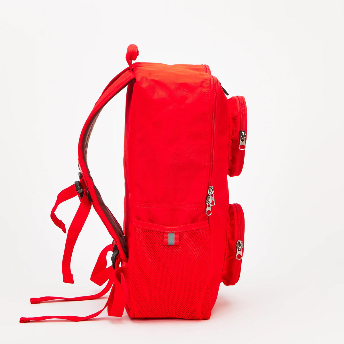 Side view of a bright red LEGO® Brick Backpack - ONLINE ONLY with two circular front pockets and mesh side pockets.