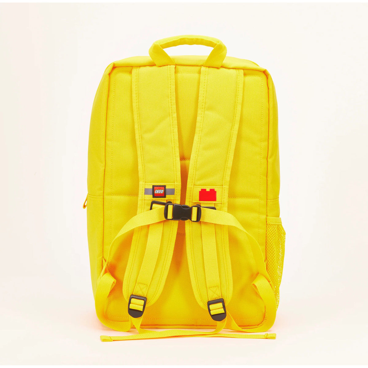 Back view of a yellow LEGO® Brick Backpack - ONLINE ONLY with adjustable straps, a chest buckle, and a mesh pocket.