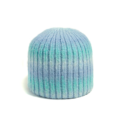 The Brume Cascade Mountain Reversible Hat is a ribbed knit beanie in blue, green, and white on a white background.