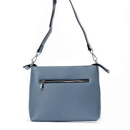 Miss Caprice Front Zipper Crossbody in blue leather with adjustable strap and zip pocket on white background.