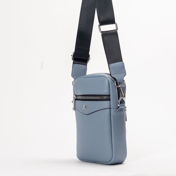 The Miss Caprice Compact Crossbody is a small blue bag with a black adjustable strap and zipper pocket for daily use.