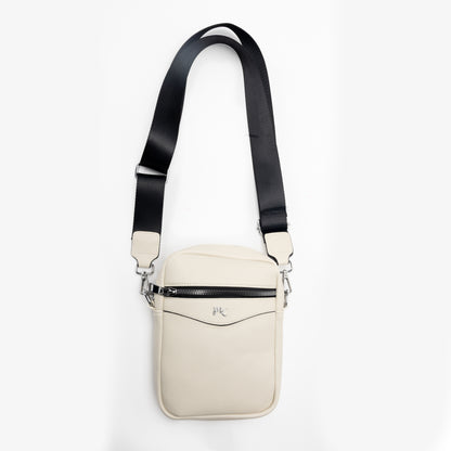The Miss Caprice Compact Crossbody is a cream bag with a black adjustable strap and zipper pocket.