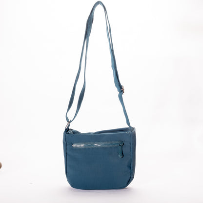 The Miss Caprice Small Nylon Crossbody is a blue bag with zip pocket and adjustable strap, ideal for travel.