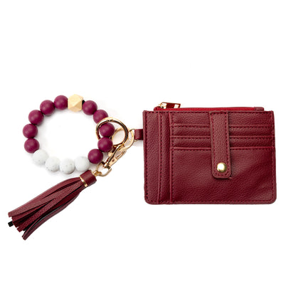 Miss Caprice Cardholder with Bracelet Keychain features a gold zipper, beaded bracelet, and tassel accessory.