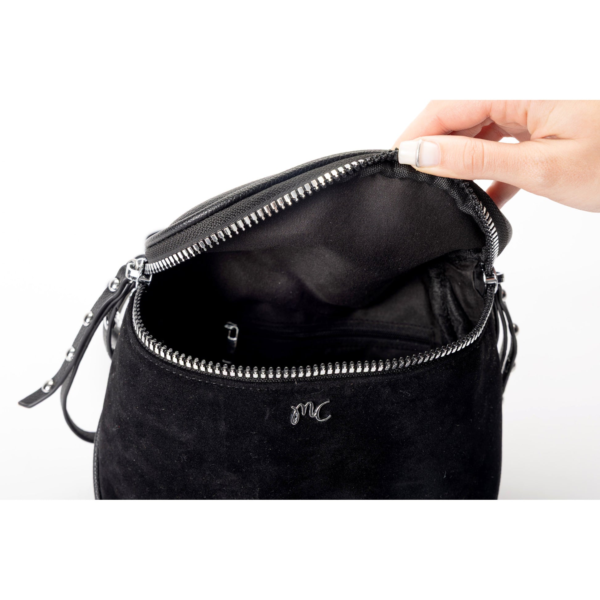 A hand opens the Miss Caprice Clara Crossbody, revealing the spacious interior of this faux suede bag.