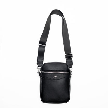 The Miss Caprice Compact Crossbody is a black leather bag with a wide strap and front pocket, shown on white.