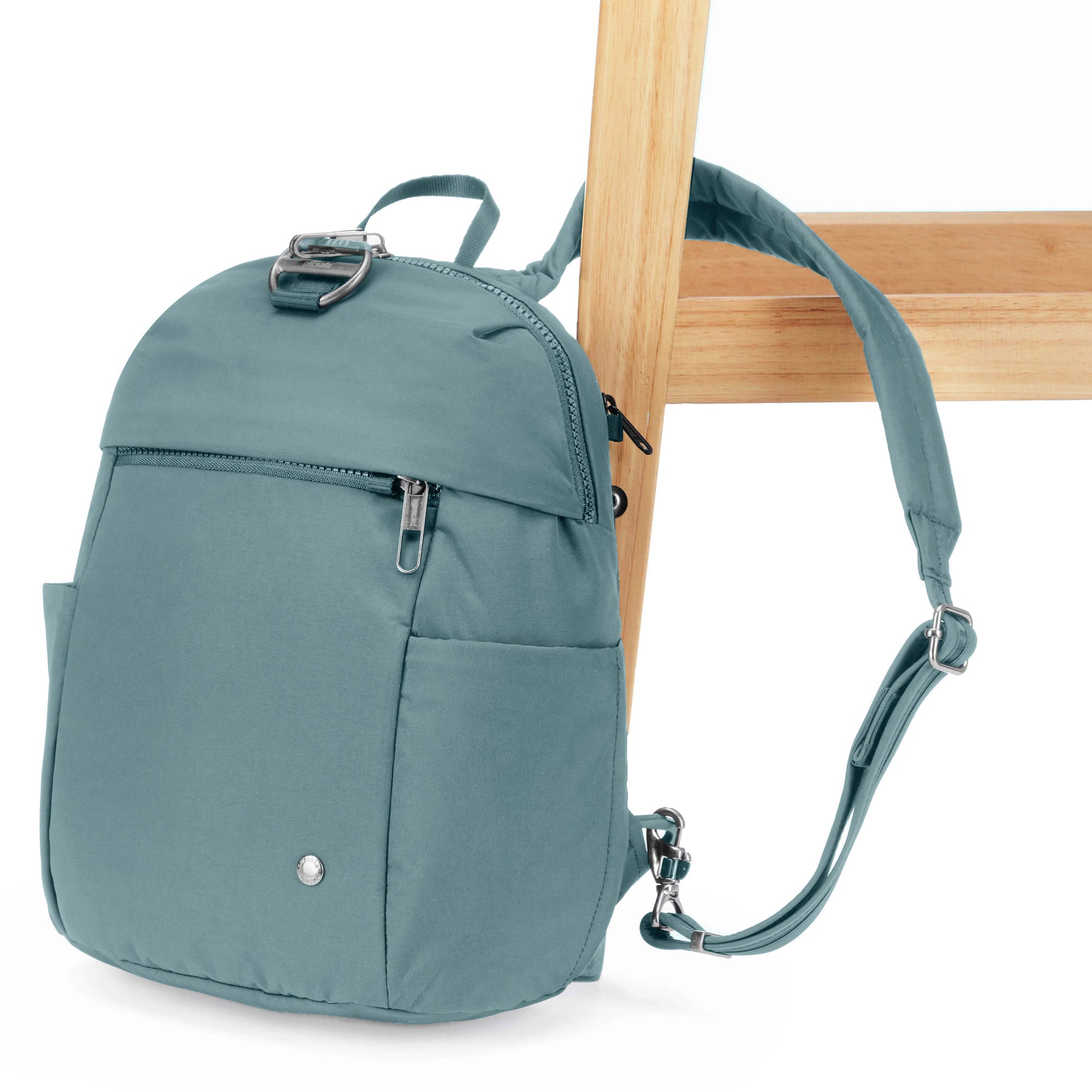 Pacsafe® CX Anti-theft 8L Backpack Petite, fresh mint, with one backpack strap secured around a chair leg