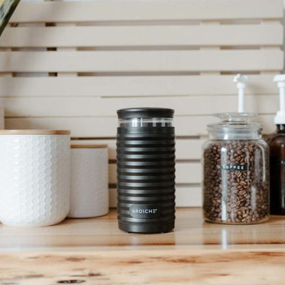 Matte black Grosche Bremen electric blade coffee grinder with ribbed texture on wooden counter