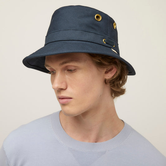 Product Image – Person wearing a navy Tilley T1 Iconic Bucket Hat with gold eyelets, enjoying sun protection.