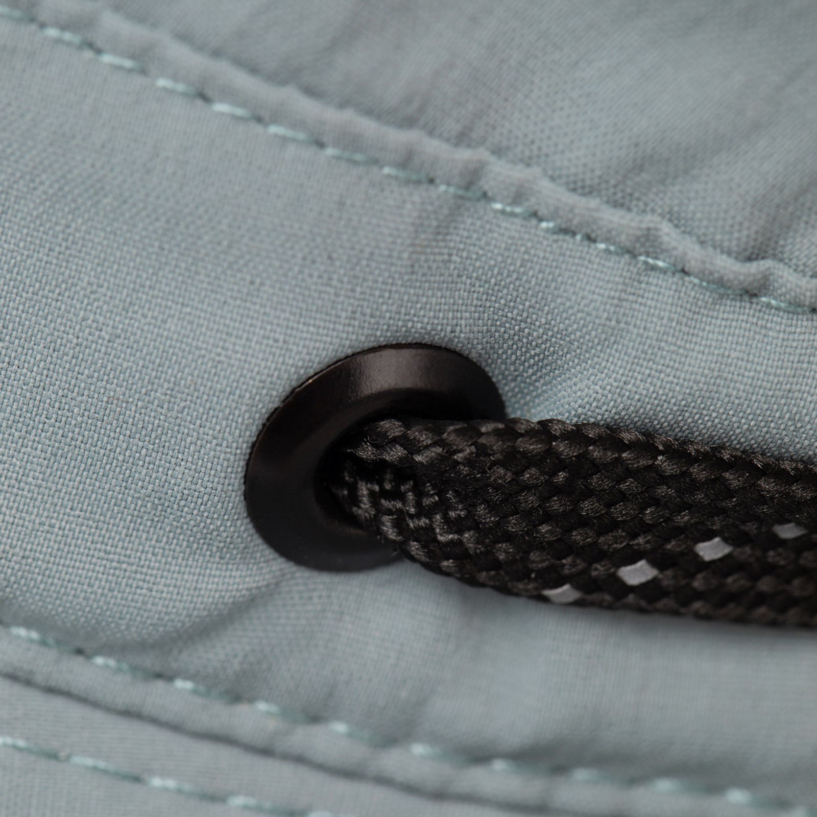Close-up of a black drawstring and metal eyelet on the Tilley T5 Adventure Ultralight Hat with UPF 50+ fabric.