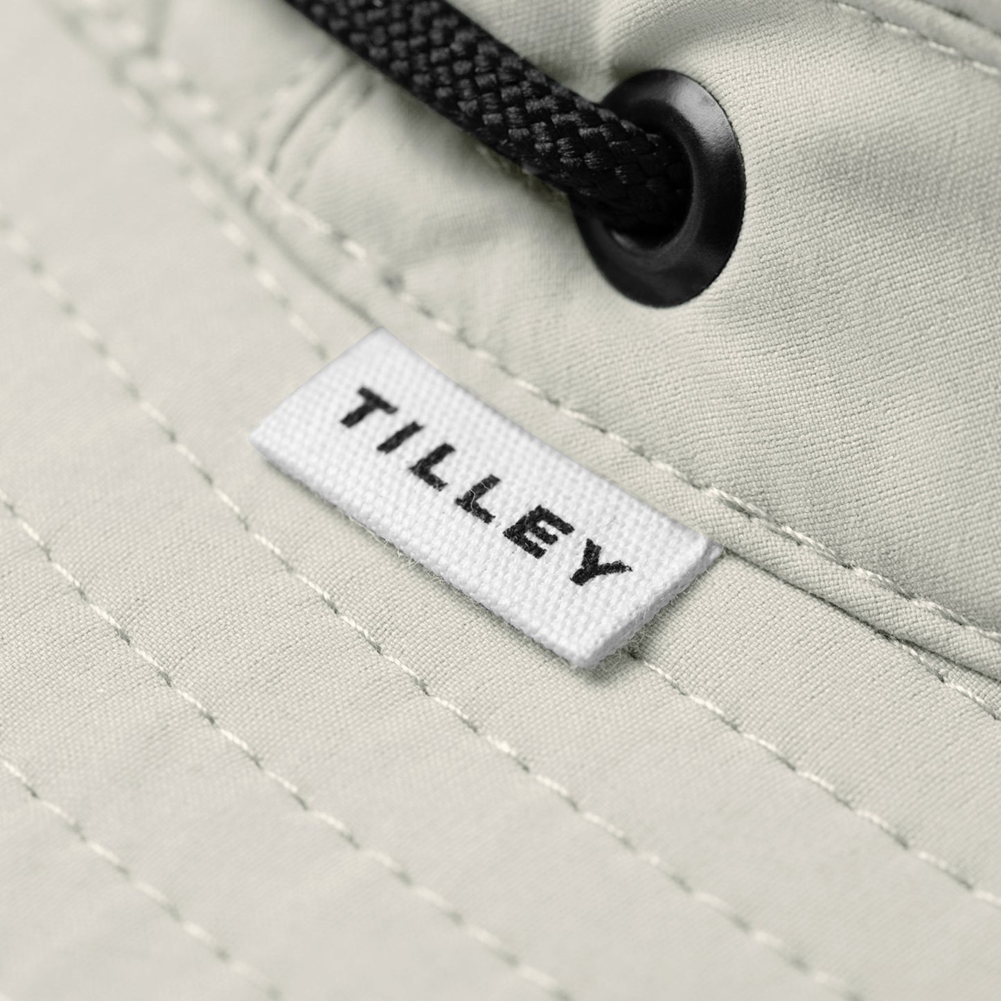 Close-up of Tilley T5 Adventure Ultralight Hat in beige with black drawstring, logo label, and UPF 50+ protection.