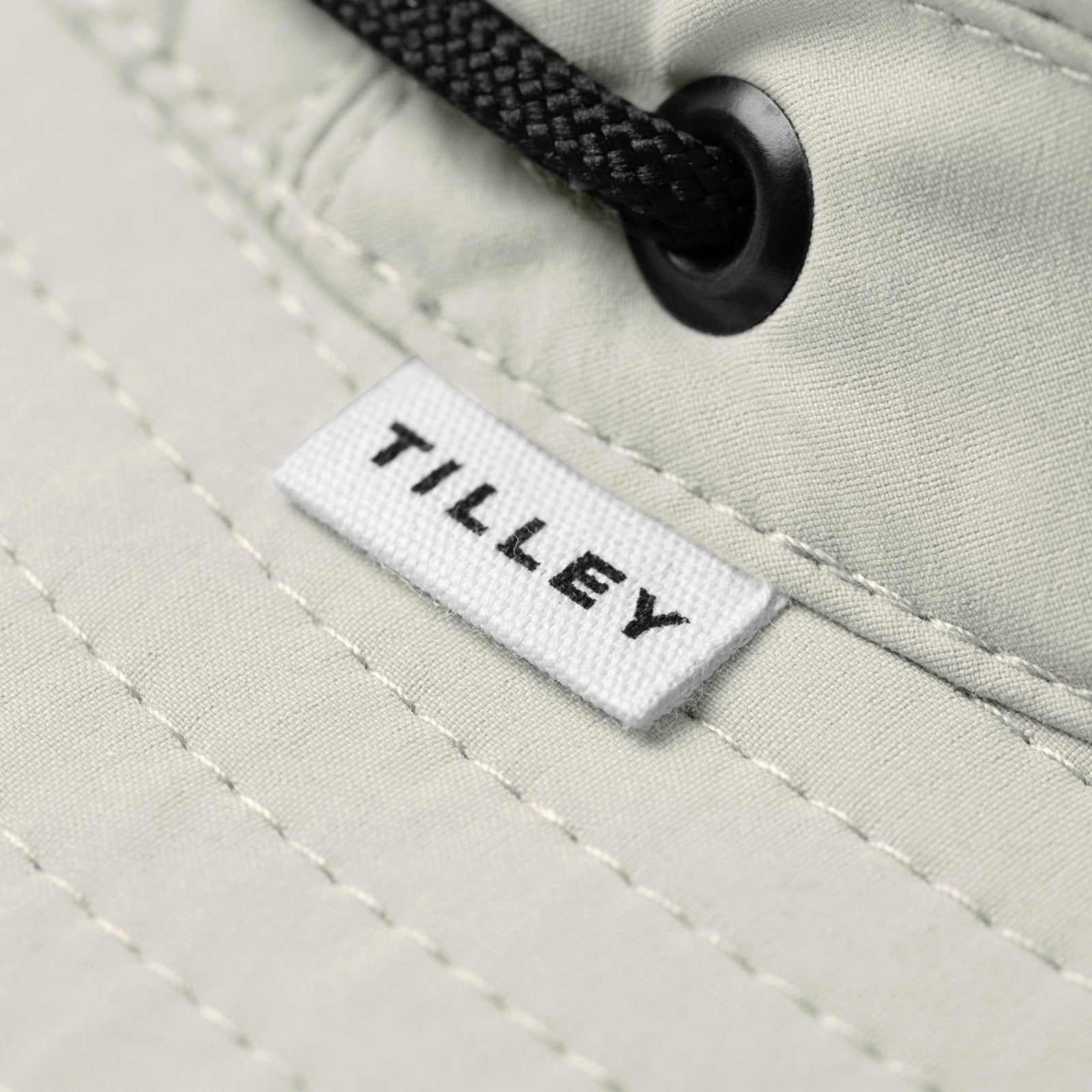 Close-up of Tilley T5 Adventure Ultralight Hat in beige with black drawstring, logo label, and UPF 50+ protection.