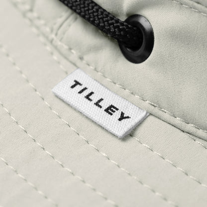 Close-up of Tilley T5 Adventure Ultralight Hat in beige with black drawstring, logo label, and UPF 50+ protection.