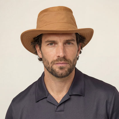 Bearded man in a tan Tilley LTM5 Airflo® Hat with mesh, dark polo, against a neutral background.