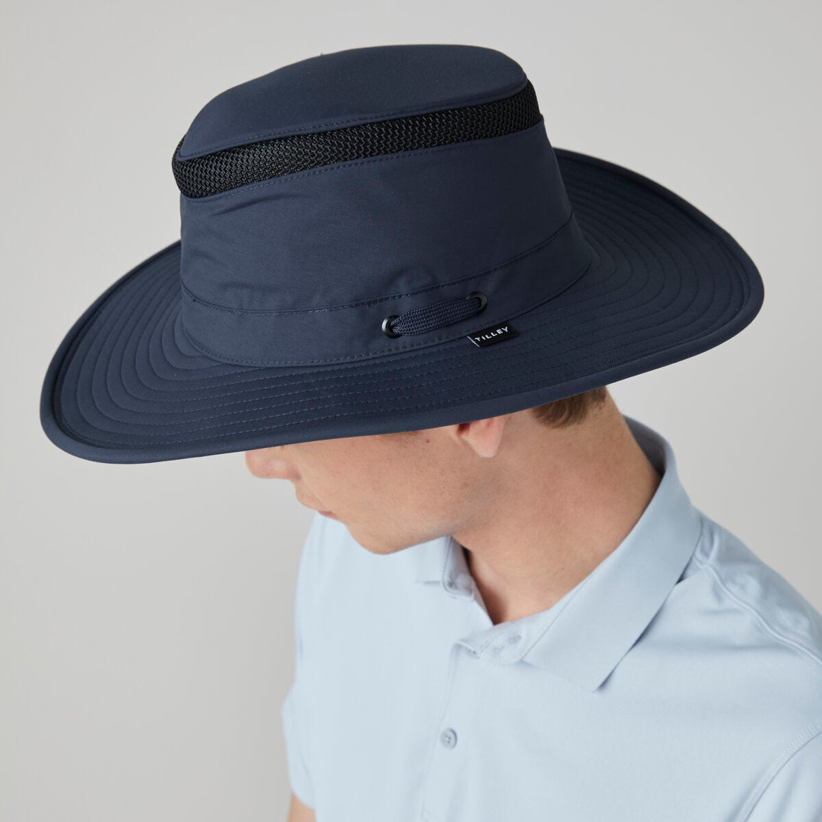 Man wearing a Tilley LTM6 Airflo® Hat and a light blue collared shirt, facing downward.