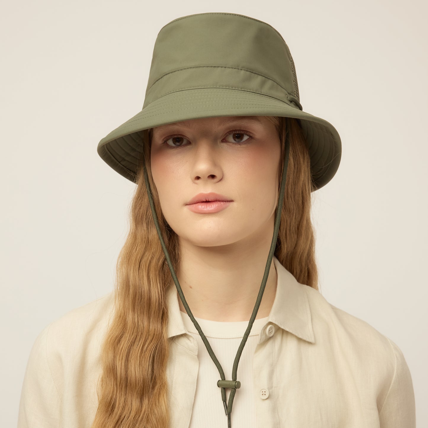 Person wearing a thyme green Tilley LTM1 Airflo® Bucket Hat with chin strap, facing forward.