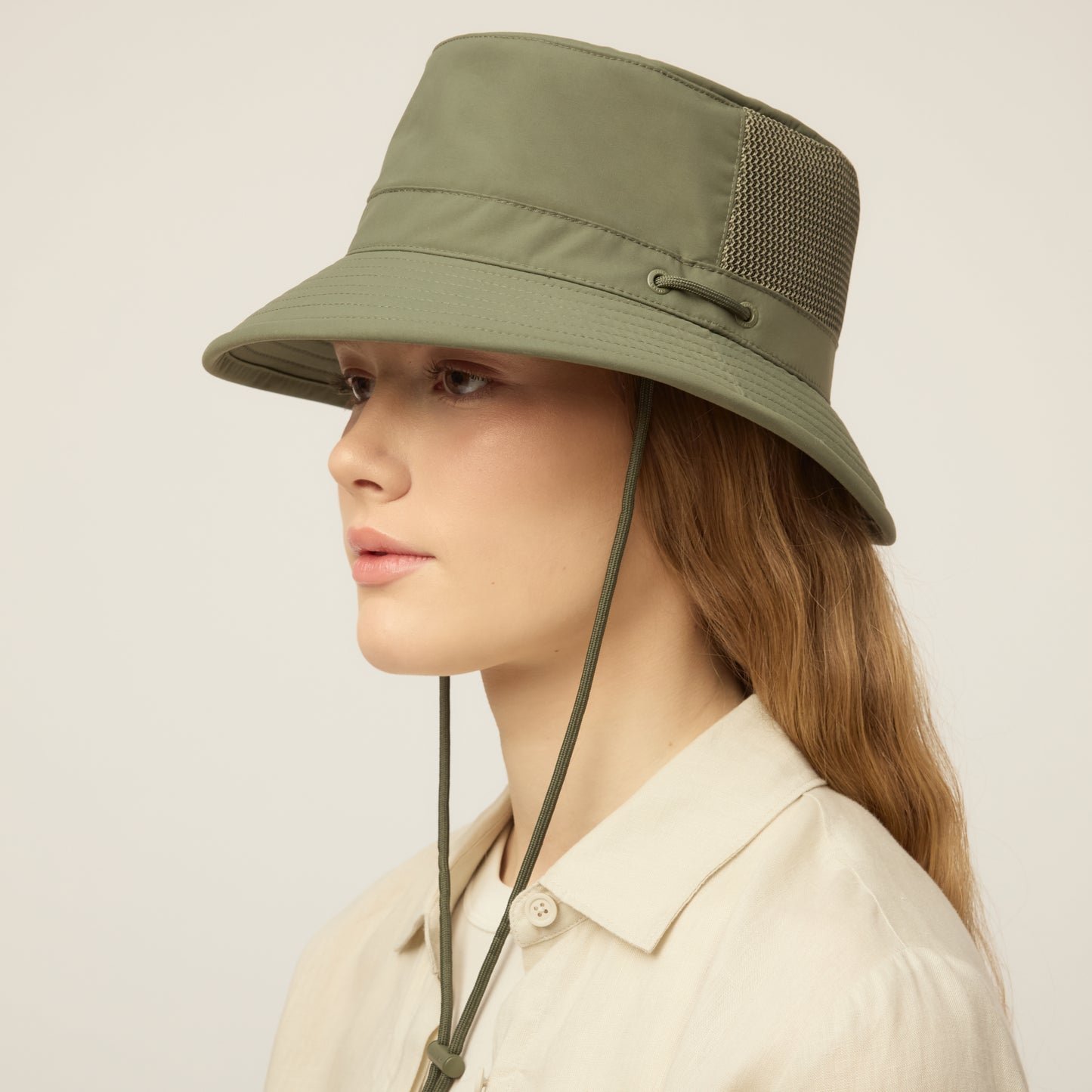 Person wearing a thyme green Tilley LTM1 Airflo® Bucket Hat with chin strap, angled front view.