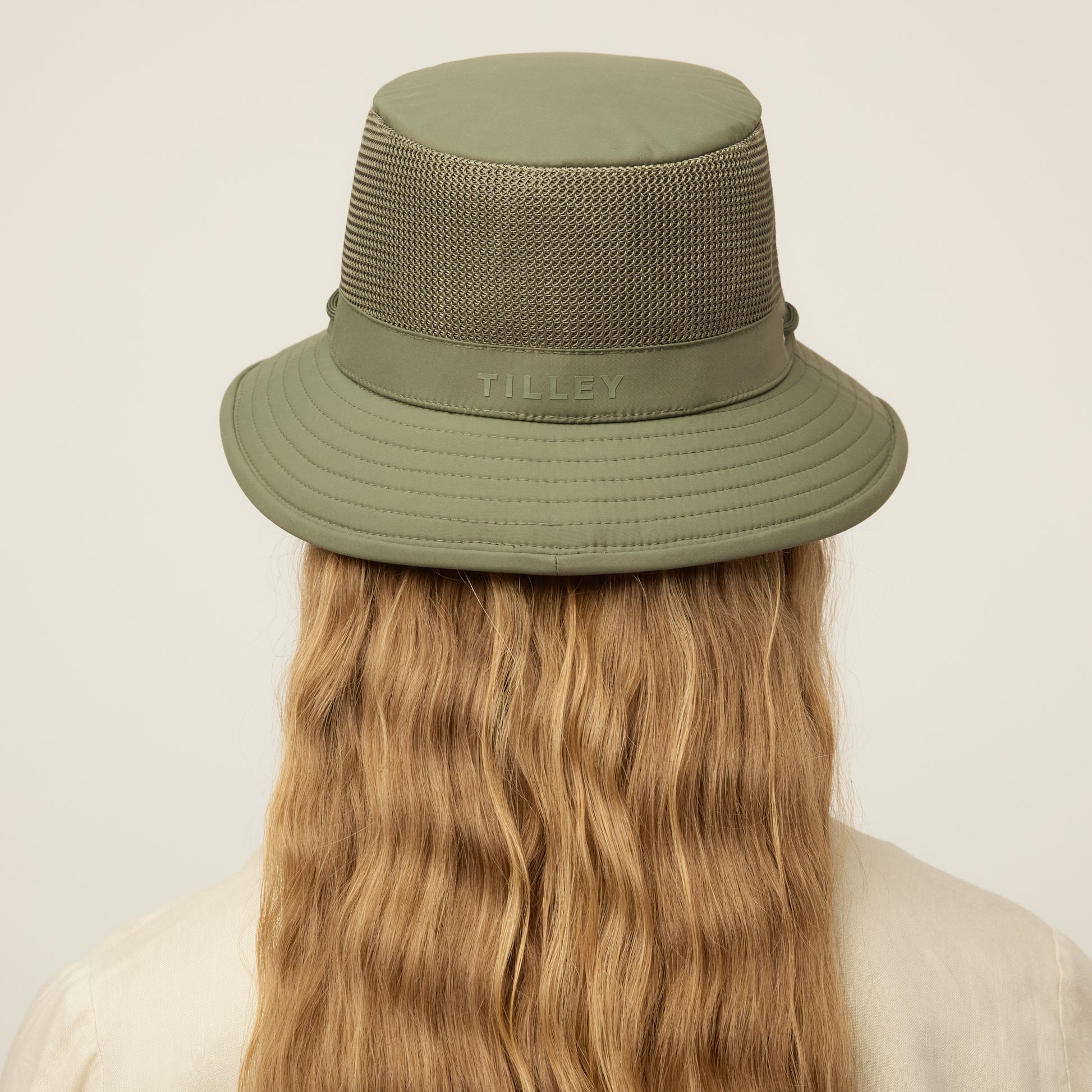 Person wearing a thyme green Tilley LTM1 Airflo® Bucket Hat with chin strap, back view.