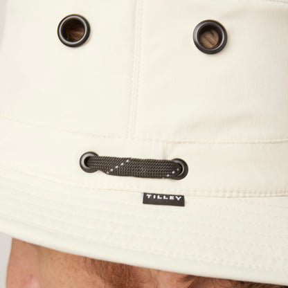 Close-up of a cream Tilley T5 Adventure Ultralight Hat with metal eyelets, black cord, and UPF 50+ protection.