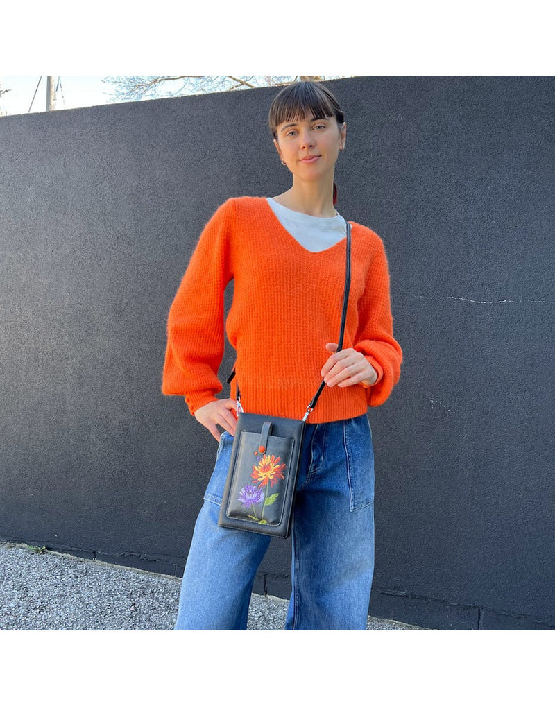 Woman wearing blue jeans and bright orange sweater standing outside wearing the Espe Glee iSmart Pocket with the crossbody strap