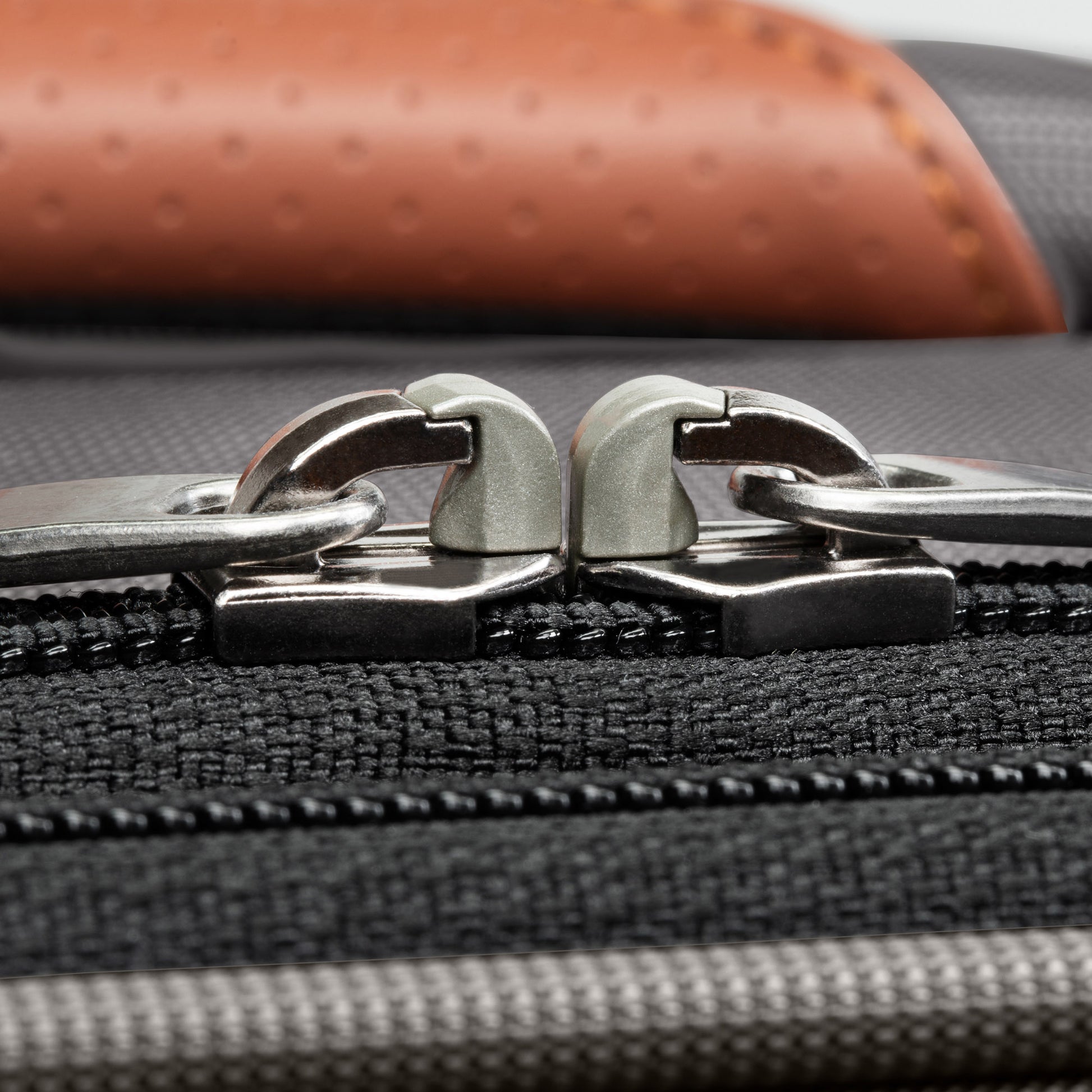 Close-up of two silver zipper pulls on the Ricardo Beverly Hills Montecito 3.0 Softside Carry-on Spinner.
