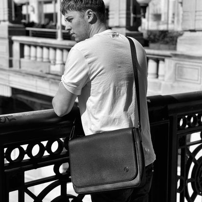 Black and white lifestyle image of man wearing the Espe Ness Messenger Bag leaning on a bridge