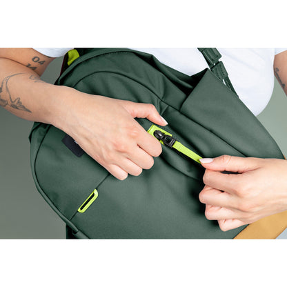 Person holding spruce green backpack opening security pocket on front of bag