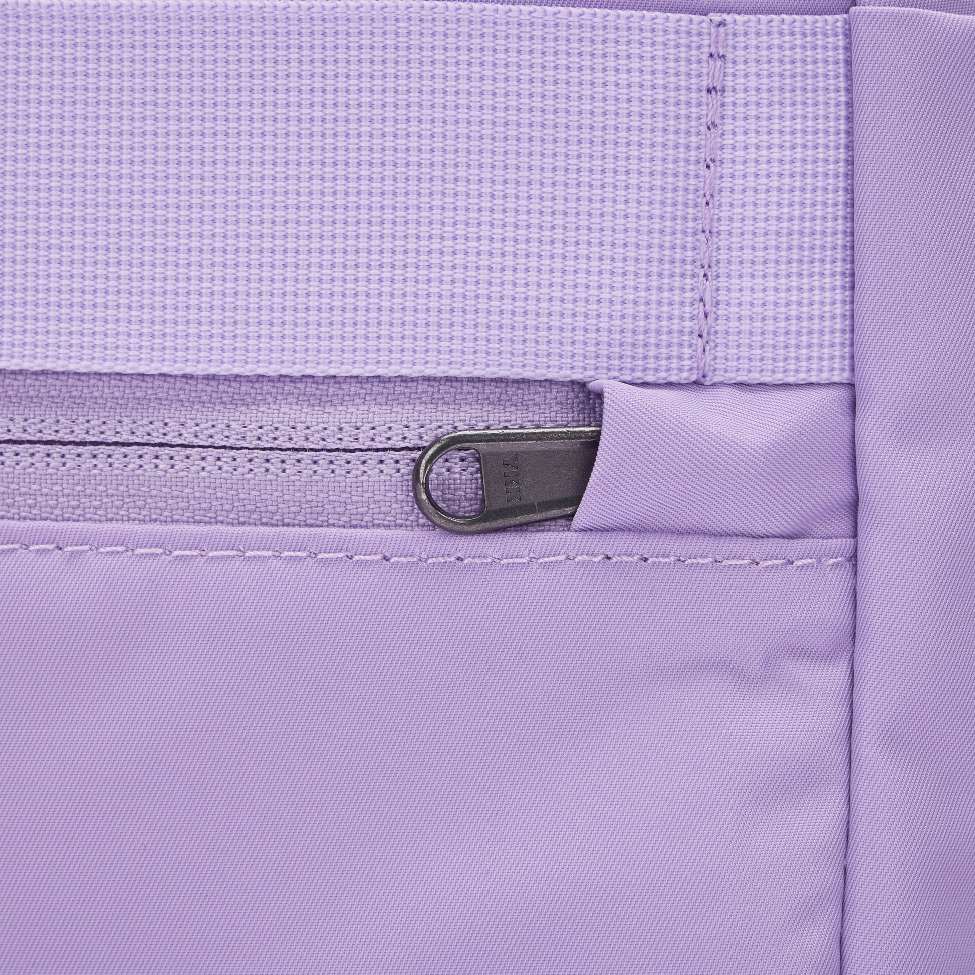 Close-up of Pacsafe® GO 15L Anti-theft Backpack's lavender pocket with zipper, waistband, and RFID block.