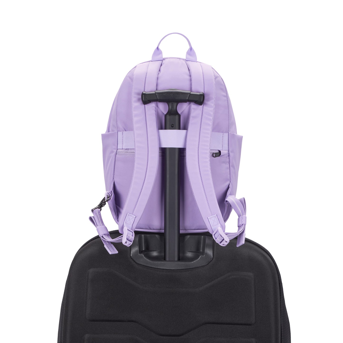 A Pacsafe® GO 15L Anti-theft Backpack in lavender is secured to a black rolling suitcase handle.