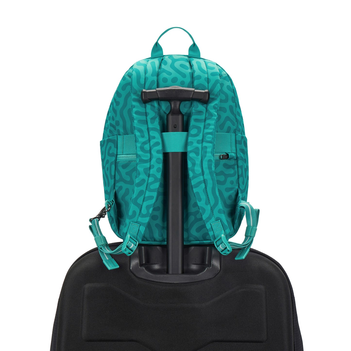 Pacsafe GO 15L backpack in reef green abstract print, placed on a luggage handle.