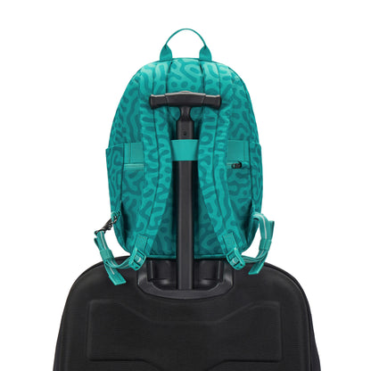 Pacsafe GO 15L backpack in reef green abstract print, placed on a luggage handle.