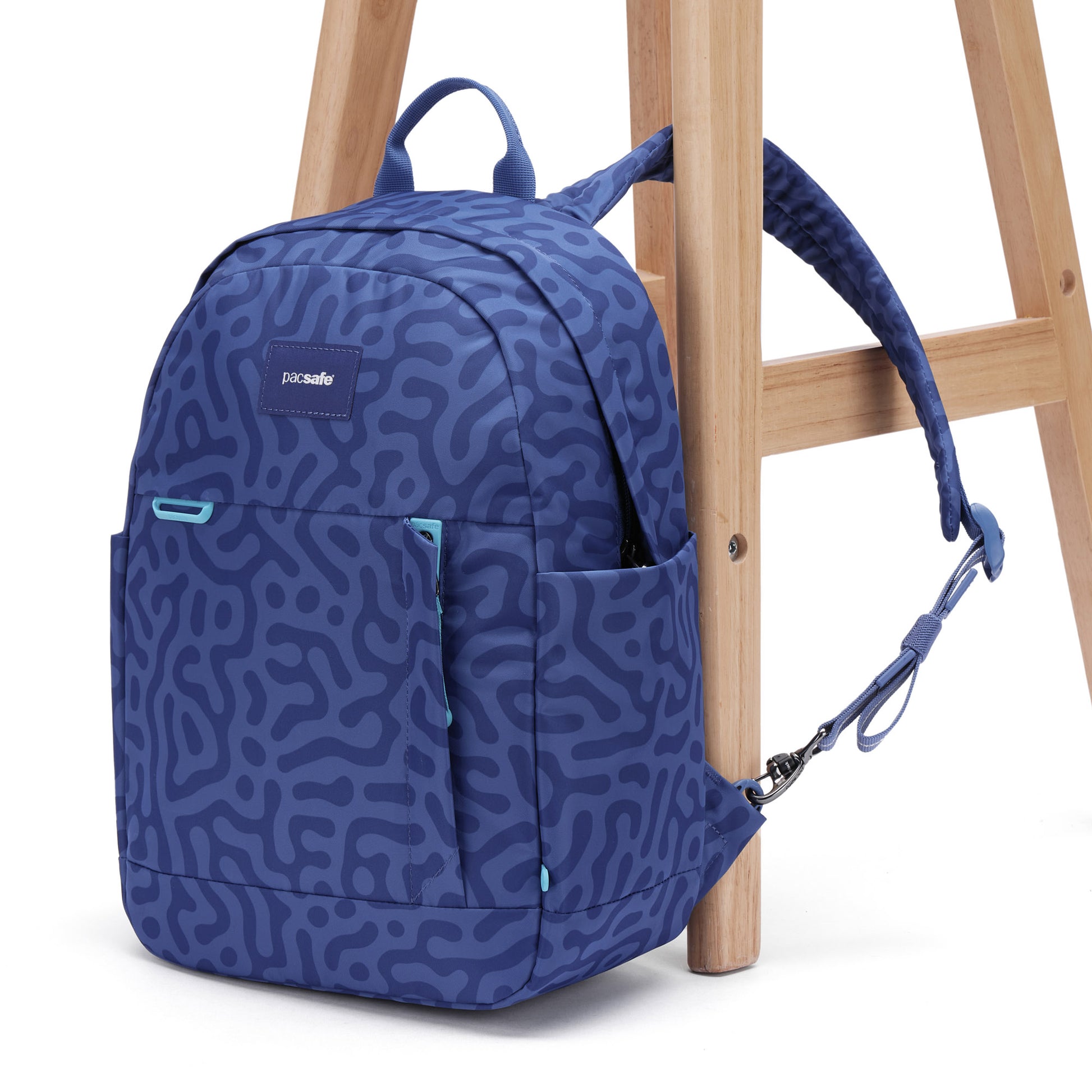 Pacsafe® GO 15L Anti-theft Backpack by Pacsafe clipped to a stool; made of recycled polyester with RFID pocket.