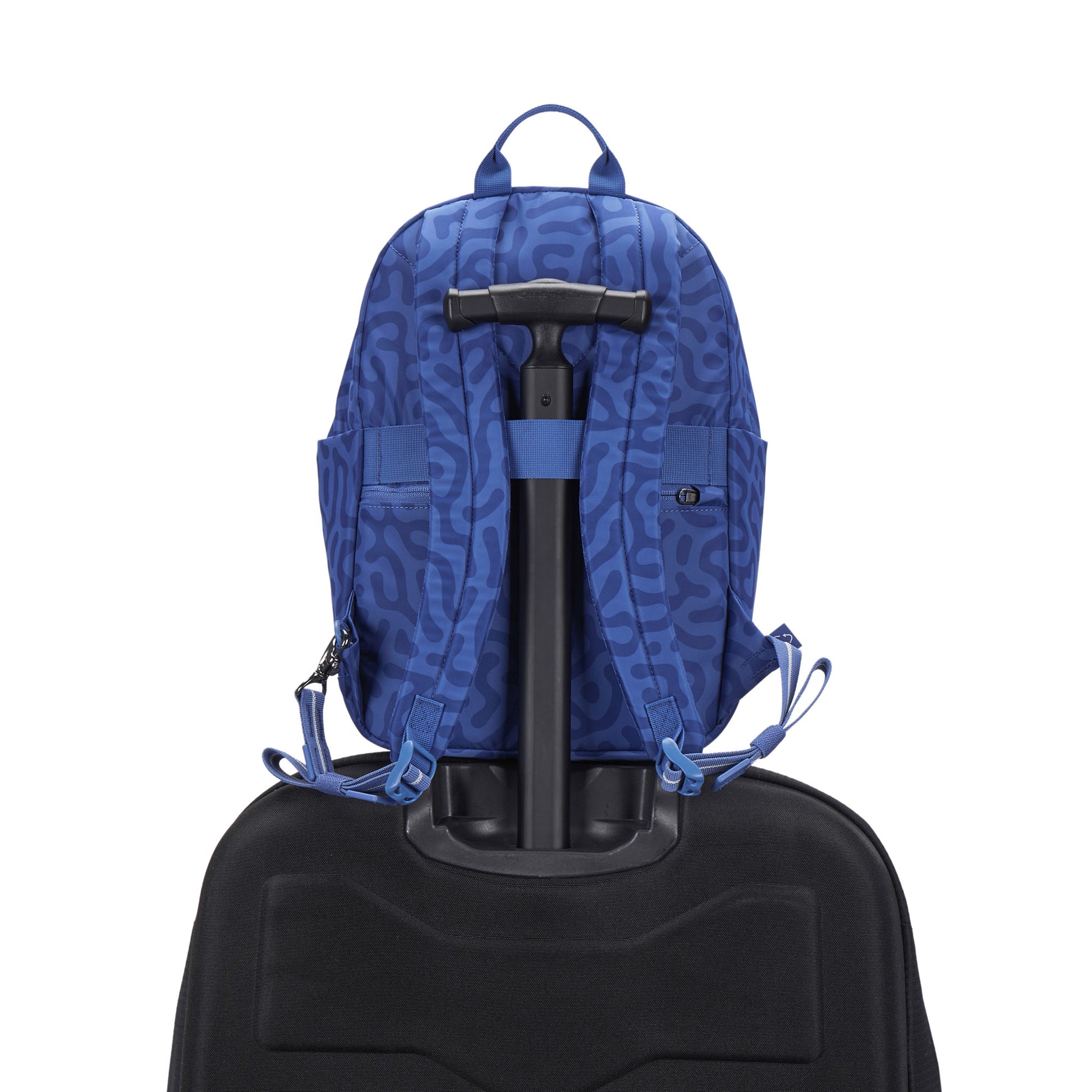 Pacsafe® GO 15L Anti-theft Backpack by Pacsafe, blue patterned, sits on a black suitcase with white background.