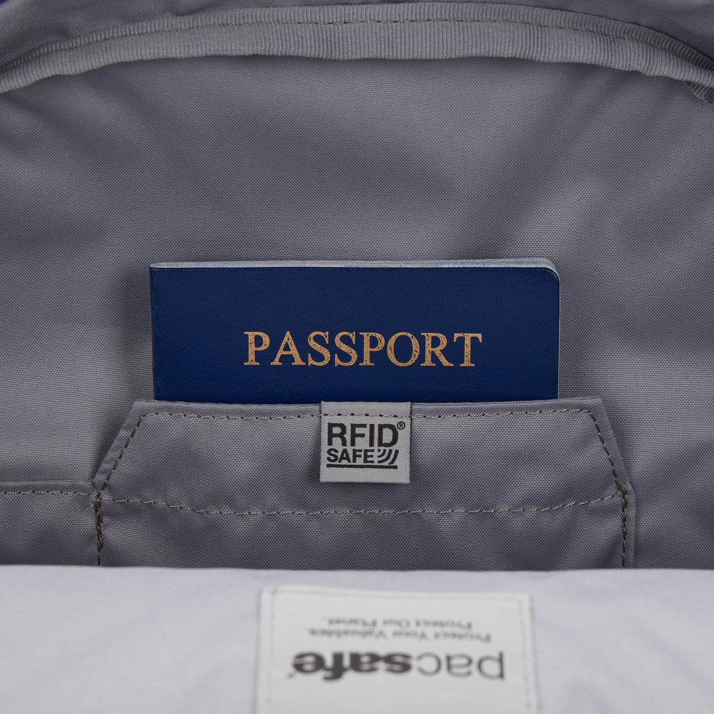 A blue passport in an RFID pocket inside the gray Pacsafe® GO 15L Anti-theft Backpack.