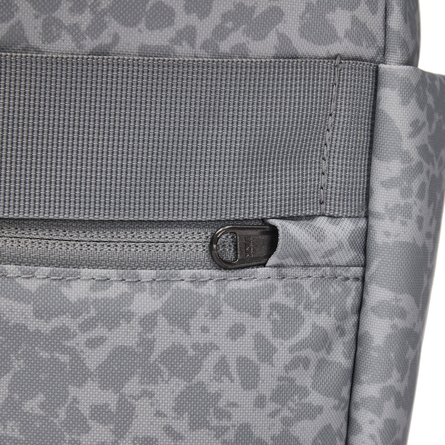 Close-up of Pacsafe® GO 15L Anti-theft Backpack in gray recycled polyester with front zipper and abstract pattern.