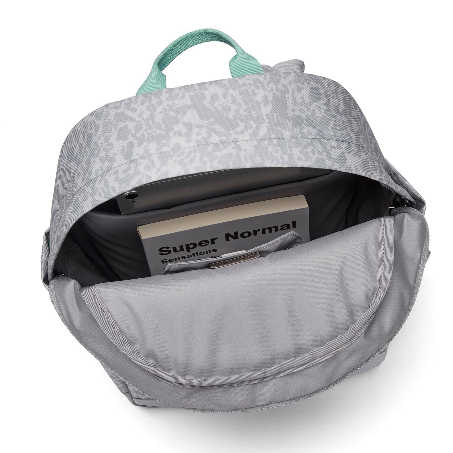 Pacsafe® GO 15L Anti-theft Backpack in gray, shown from above with a book/tablet inside; recycled polyester.