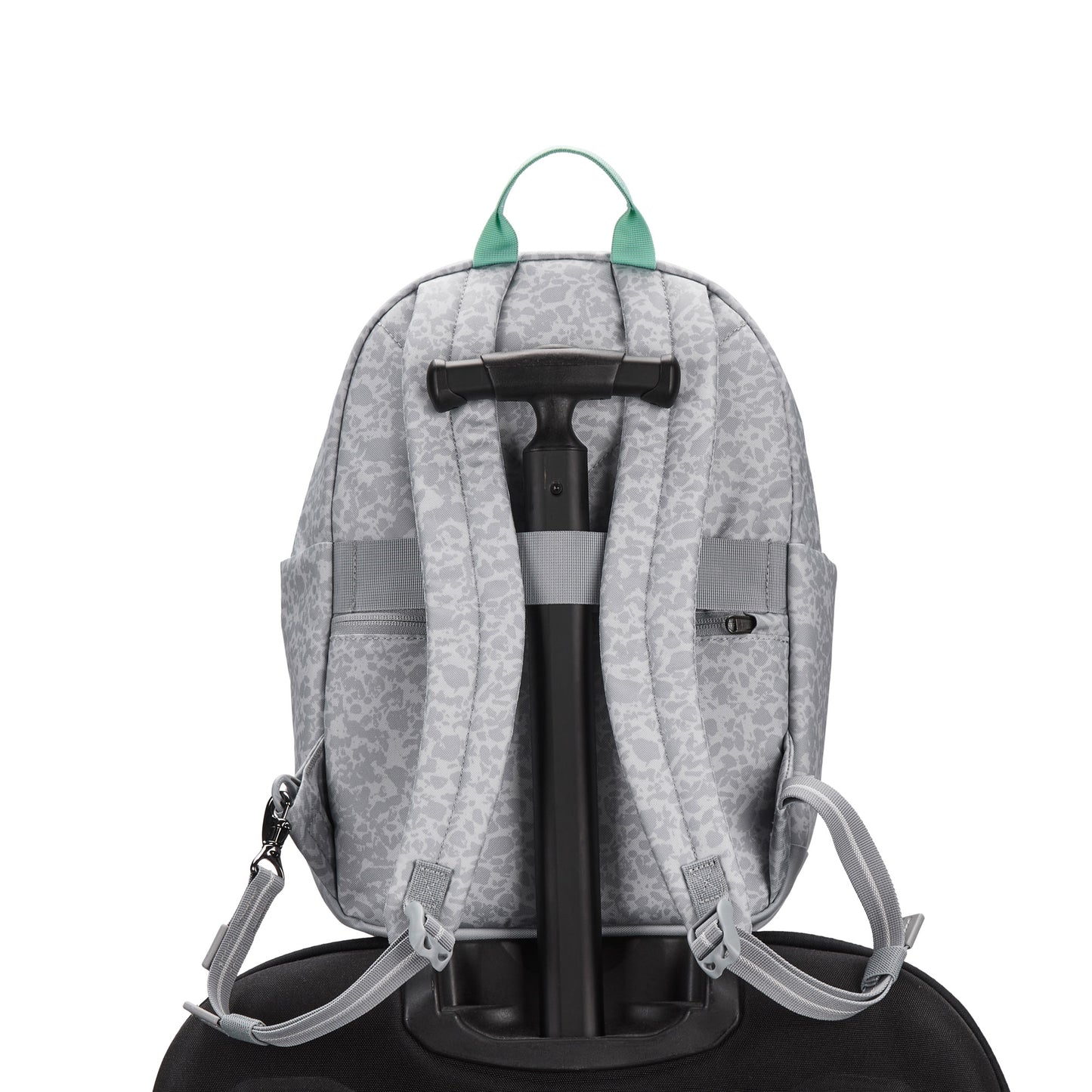 Pacsafe® GO 15L Anti-theft Backpack in gray, recycled polyester, sits on suitcase; green zipper pulls show.