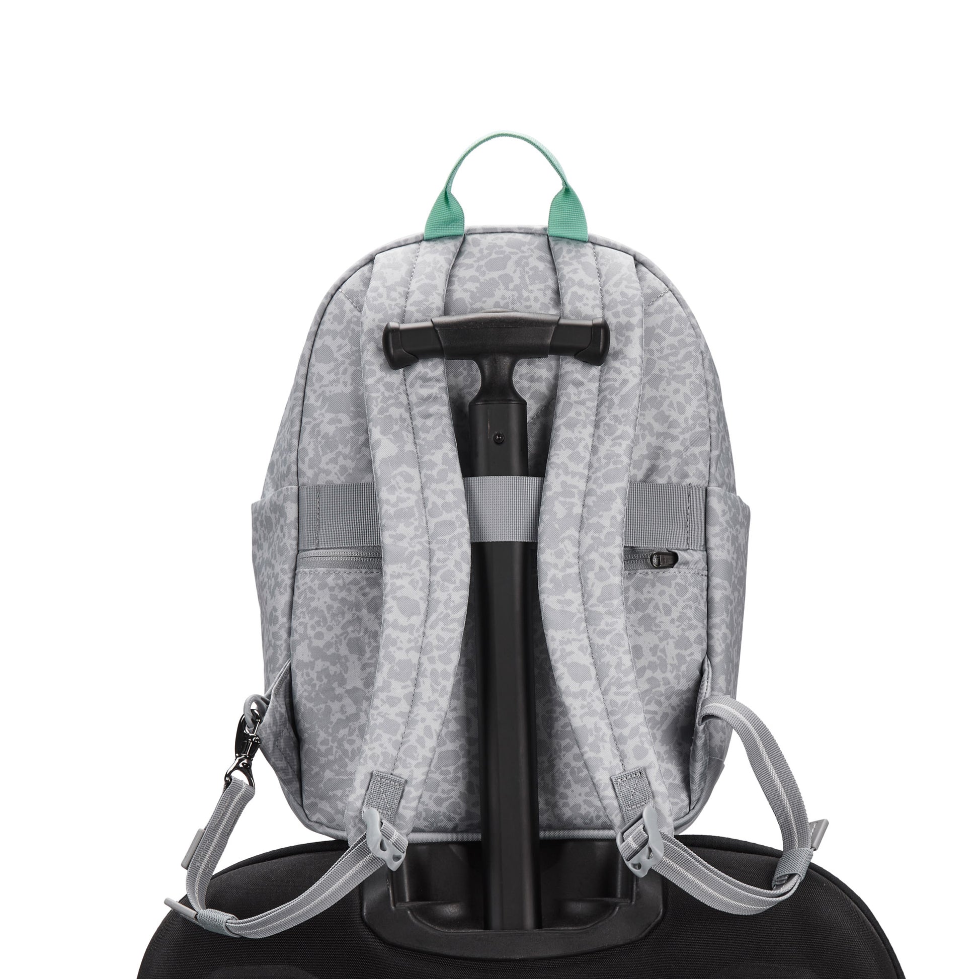 Pacsafe® GO 15L Anti-theft Backpack in gray, recycled polyester, sits on suitcase; green zipper pulls show.