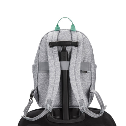 Pacsafe® GO 15L Anti-theft Backpack in gray, recycled polyester, sits on suitcase; green zipper pulls show.
