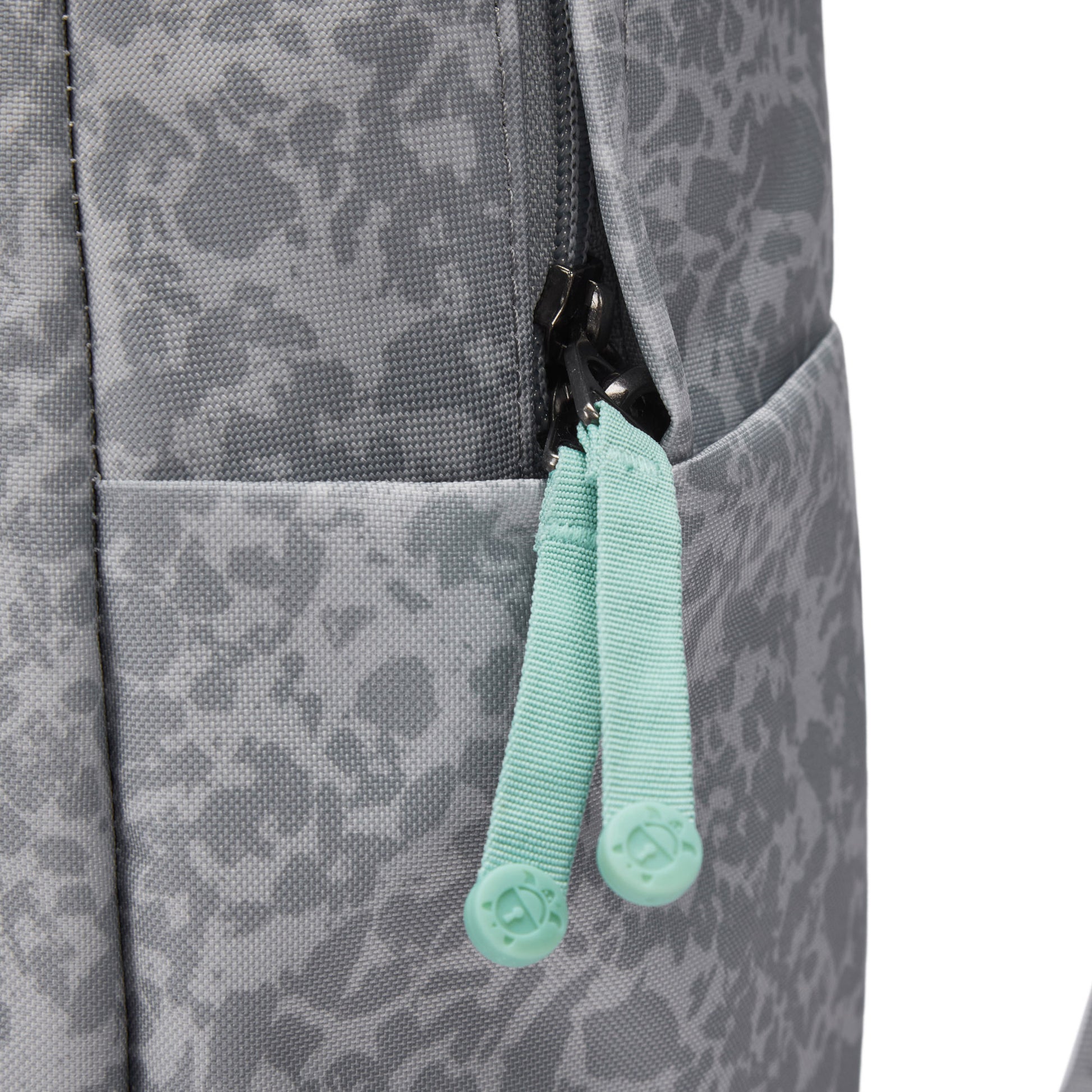 Close-up of Pacsafe® GO 25L Anti-theft Backpack in gray with mint green zipper pulls and side pocket.