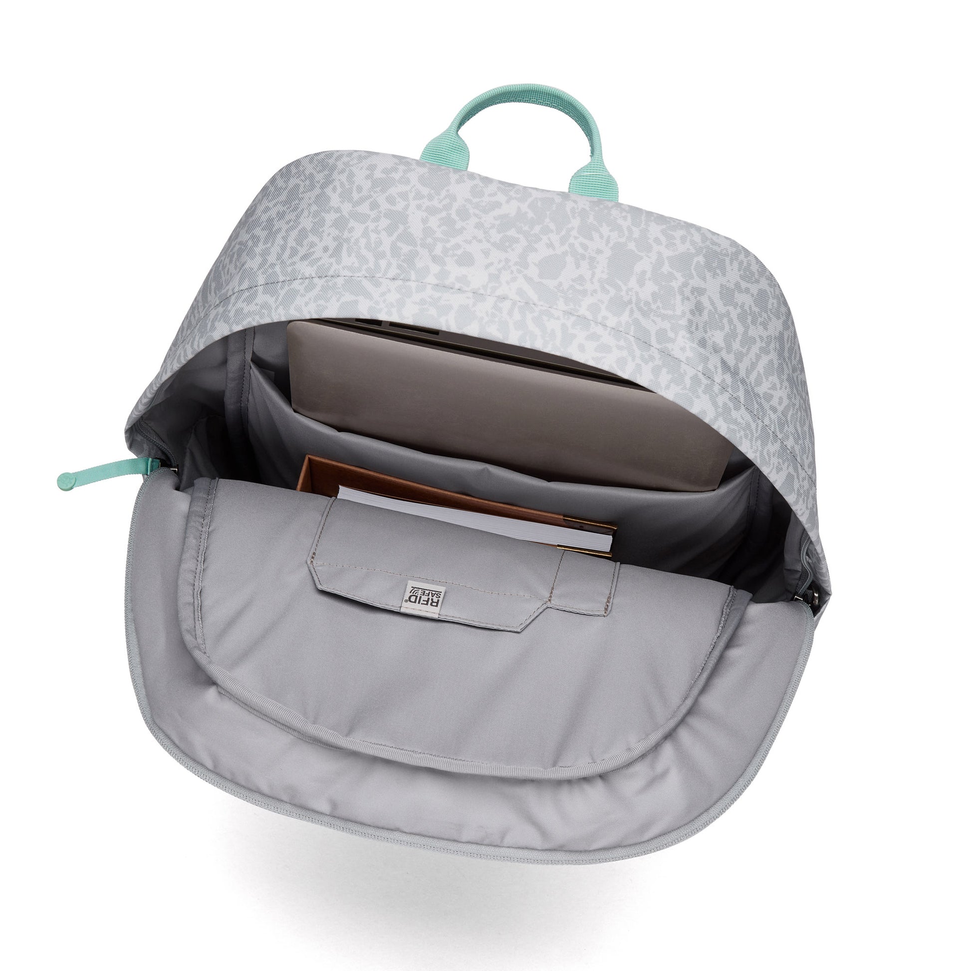 Open Pacsafe® GO 25L Backpack with a laptop and notebooks inside, showing organized compartments.