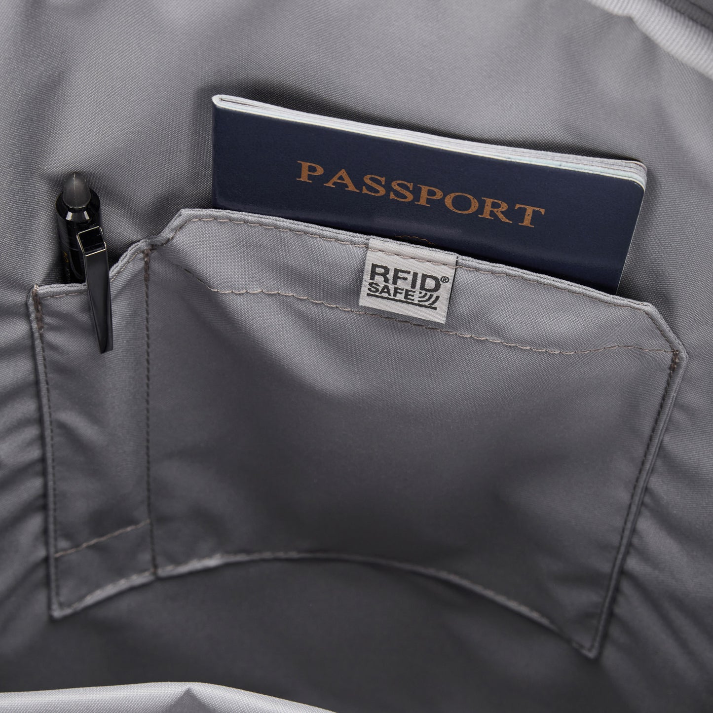 A navy passport and pen in the RFID pocket of a Pacsafe® GO 25L Anti-theft Backpack by Pacsafe.
