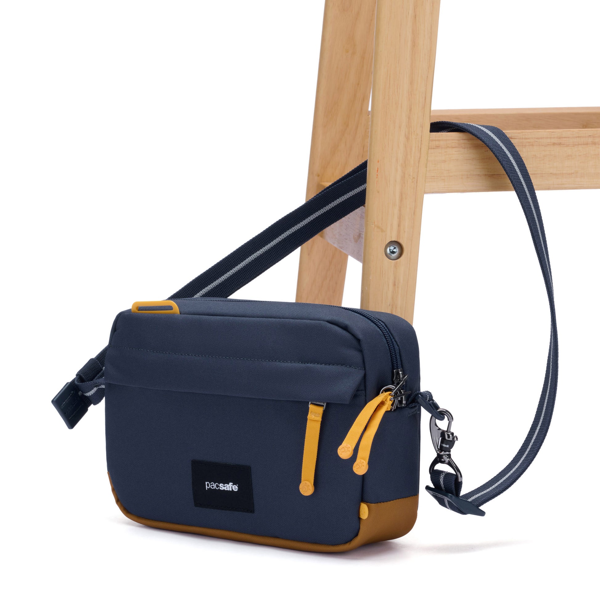 Pacsafe® GO Anti-Theft Crossbody Bag in coastal blue colour with shoulder strap secured to a chair leg.