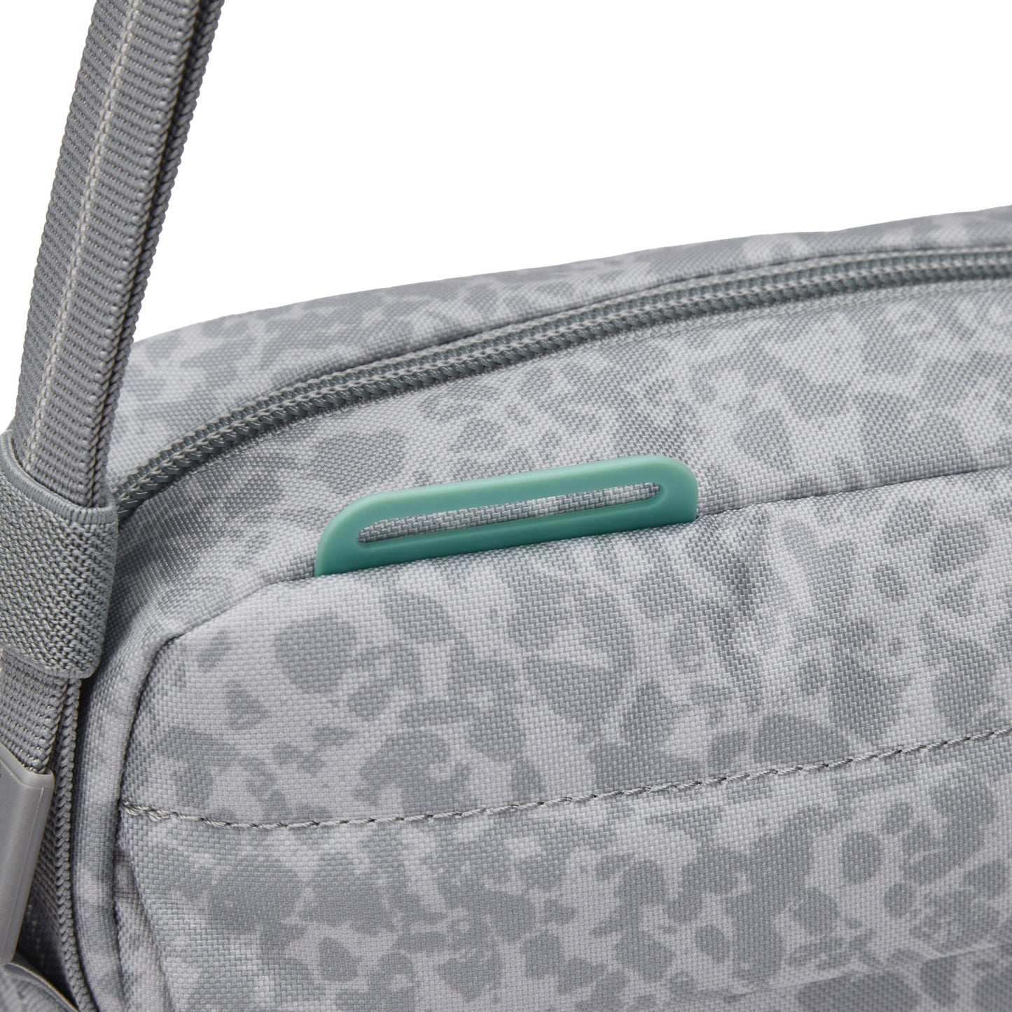Close-up of Pacsafe® GO Anti-Theft Crossbody Bag in gray with green zipper pull and RFID blocking pocket.