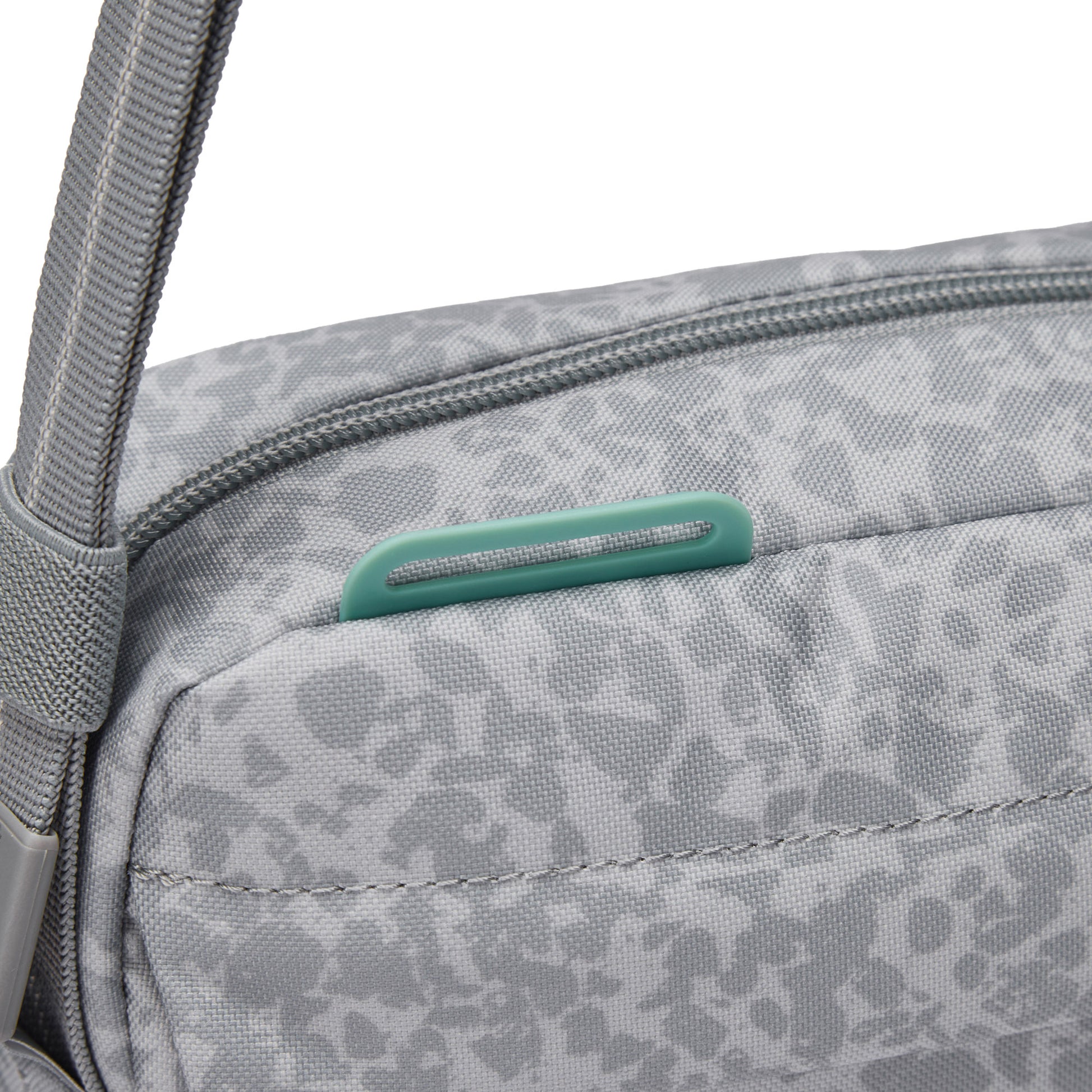 Close-up of Pacsafe® GO Anti-Theft Crossbody Bag in gray with green zipper pull and RFID blocking pocket.