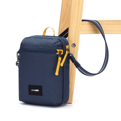 Pacsafe® GO Anti-Theft Festival Crossbody in coastal blue colour with shoulder strap secured to chair leg.