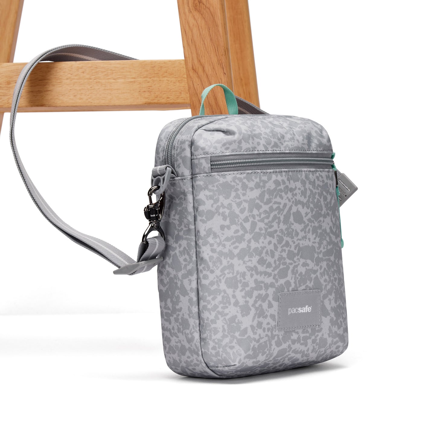Pacsafe® GO Anti-Theft Festival Crossbody by Pacsafe, gray pattern, RFID pocket, on white with wood chair leg.