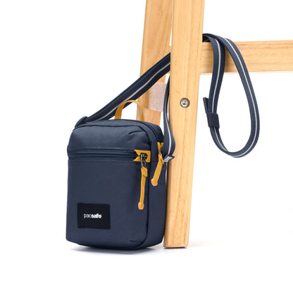 Pacsafe® GO Anti-Theft Micro Crossbody in blue with strap wrapped around chair leg.